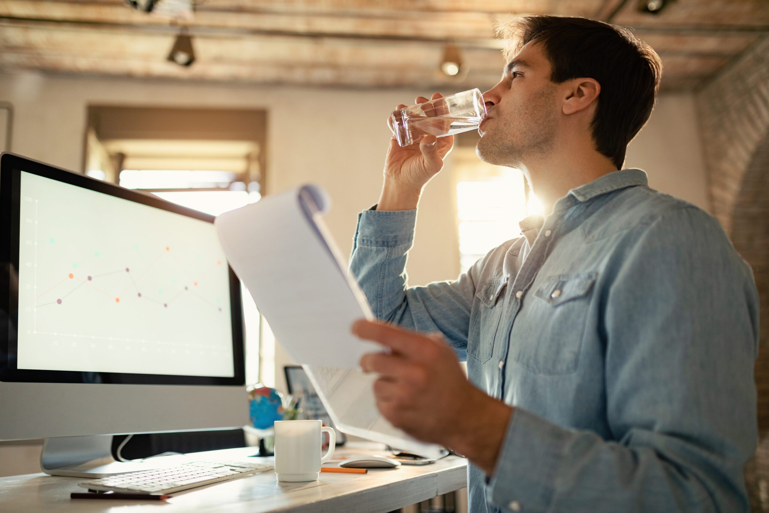 Imagen de un hombre de mediana edad bebiendo agua en una oficina