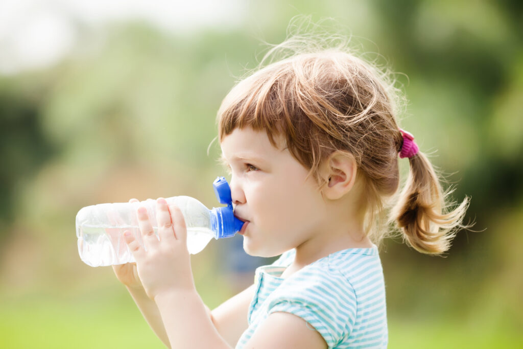 Imagen de una niña bebiendo agua con una botellas de plástico